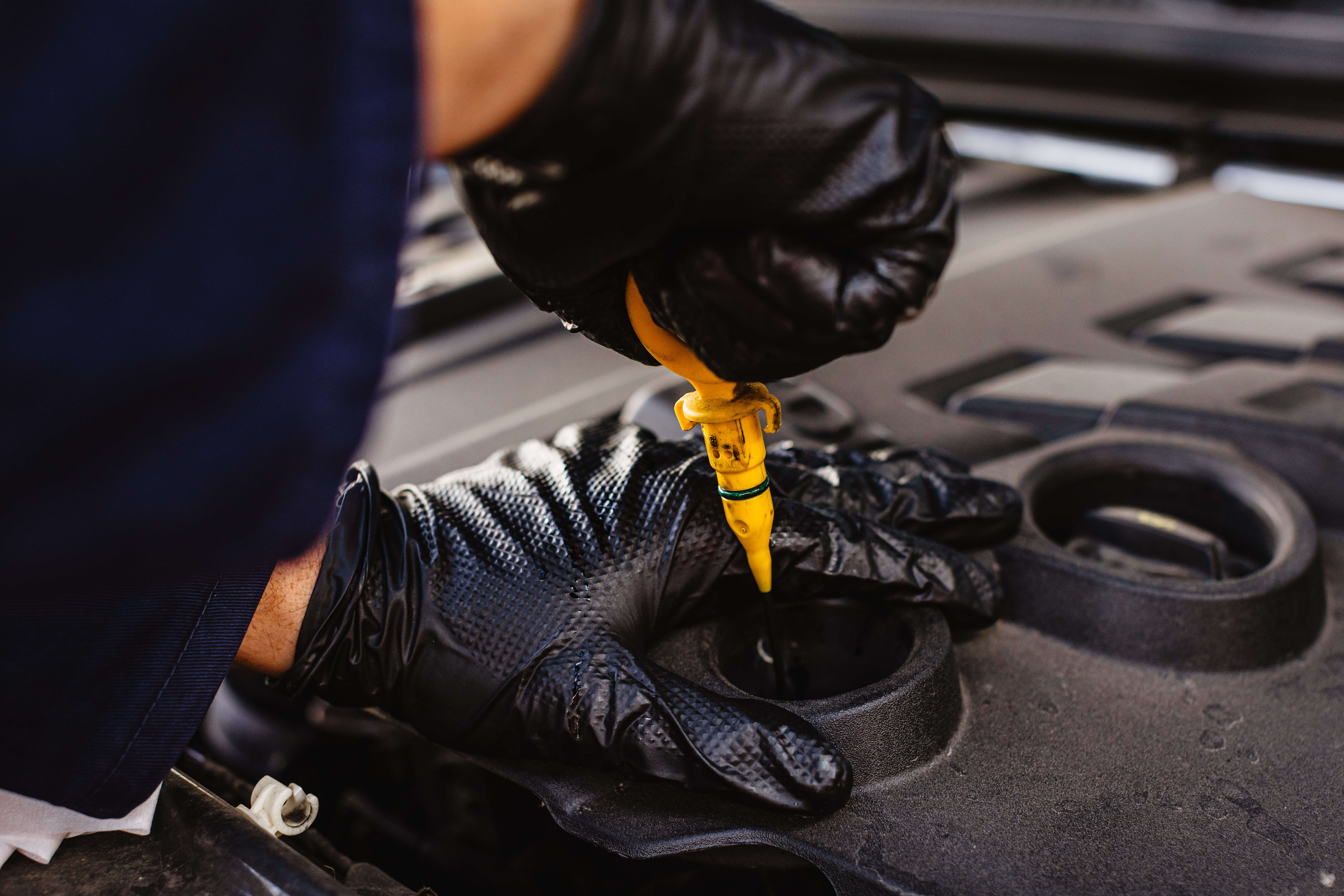 black diamond grip nitrile gloves worn by mechanic checking oil dipstick
