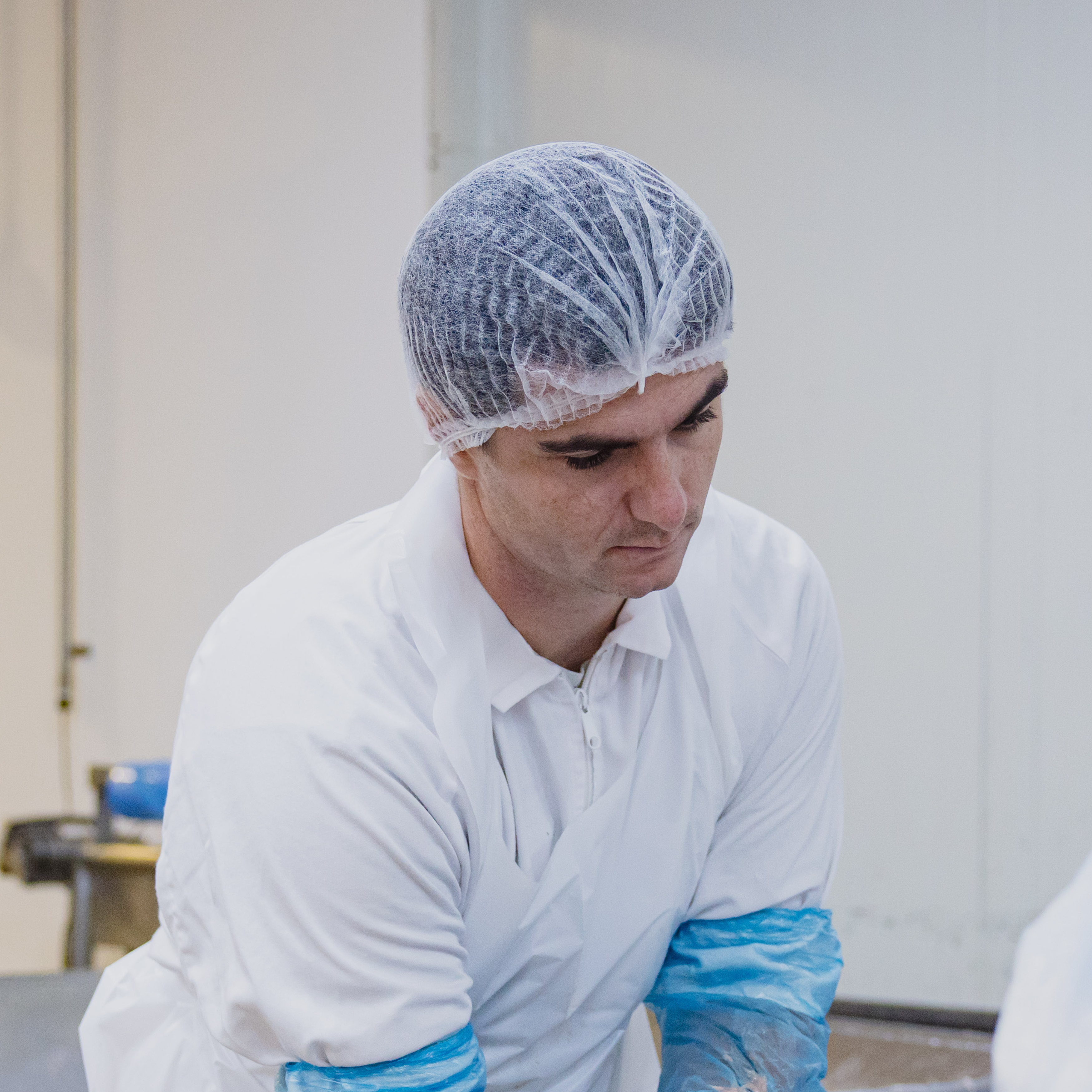 man wearing sleeve protectors, white apron and clip hat