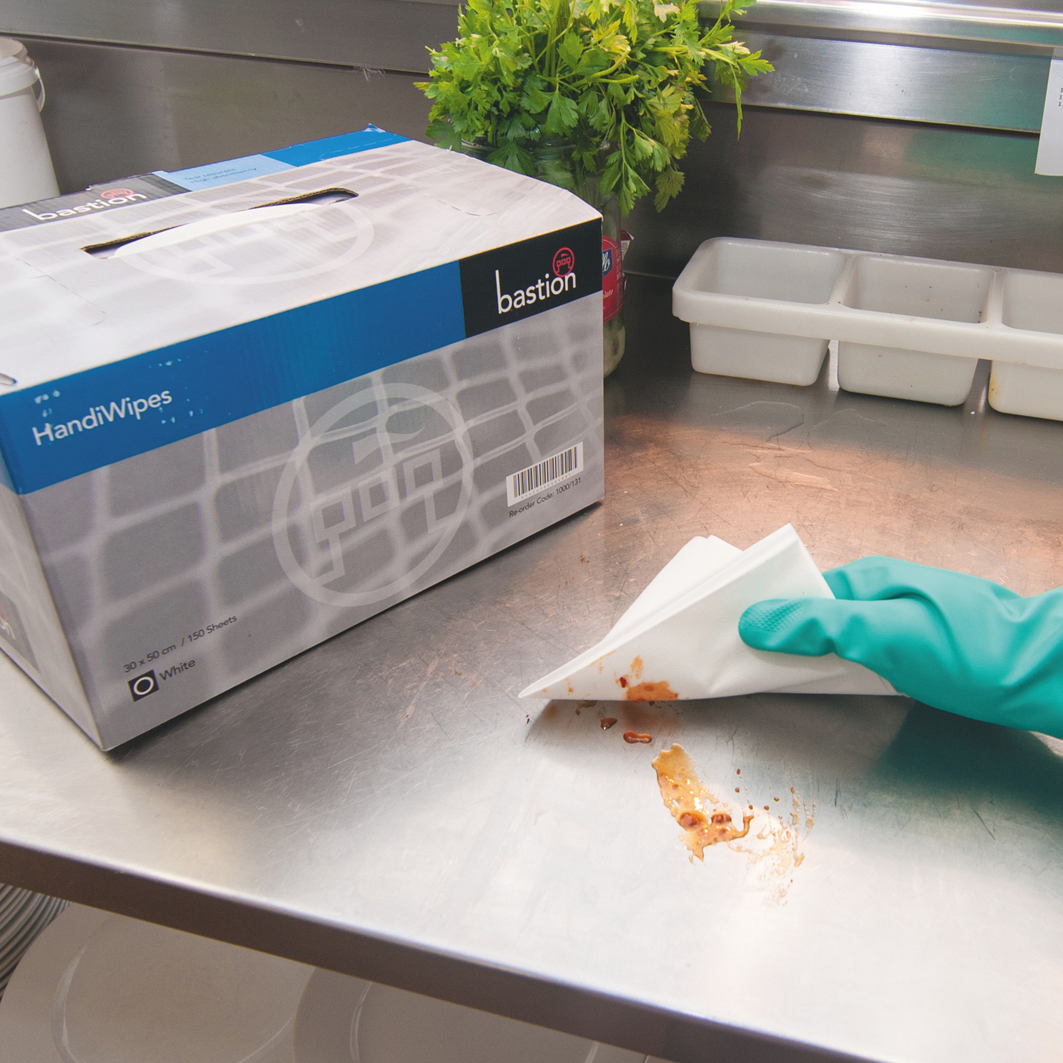 Box of Bastion handi wipes being used on stainless steel bench with reusable household gloves.