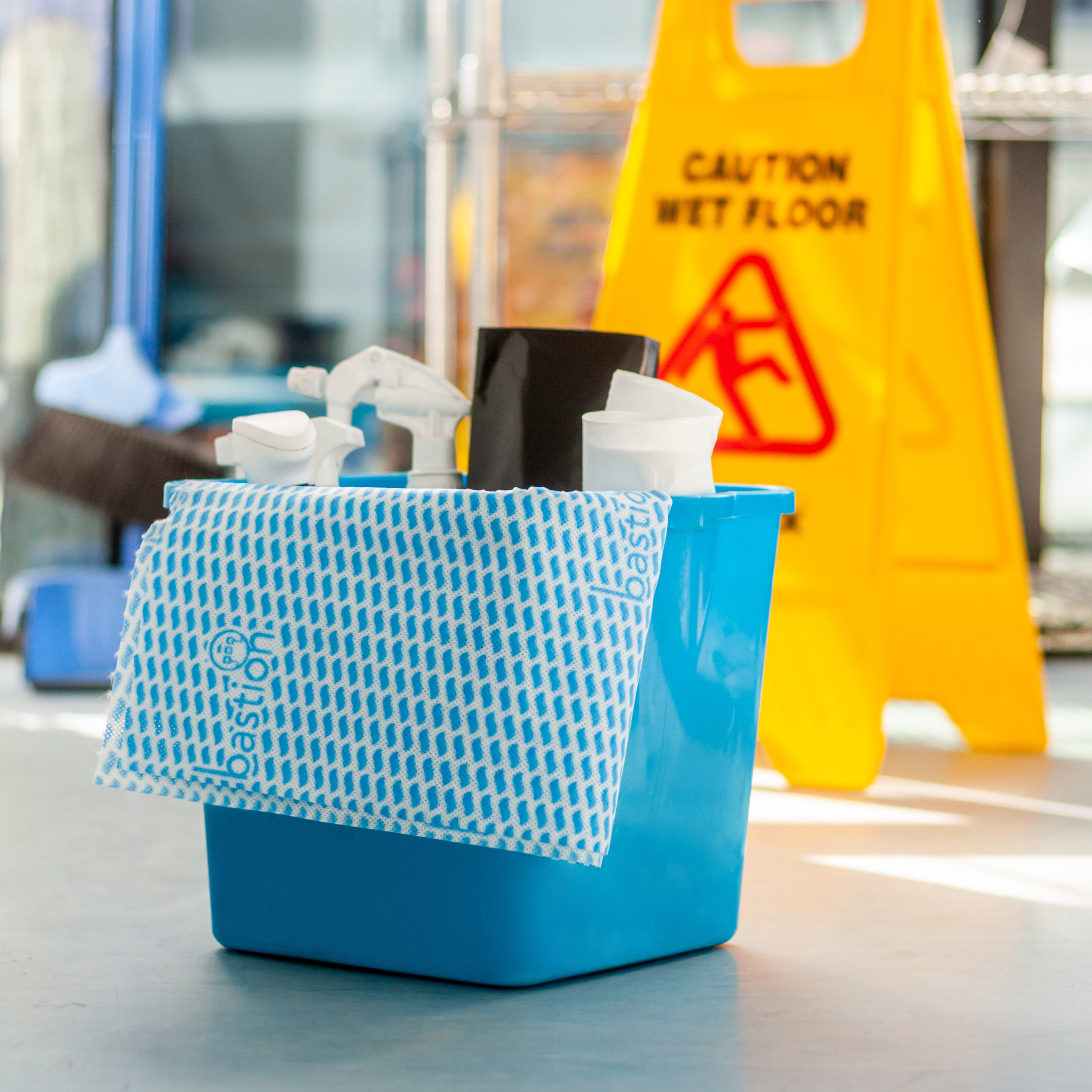 Bastion wipes on a roll, sheet on janitor pail with wet floor sign in background
