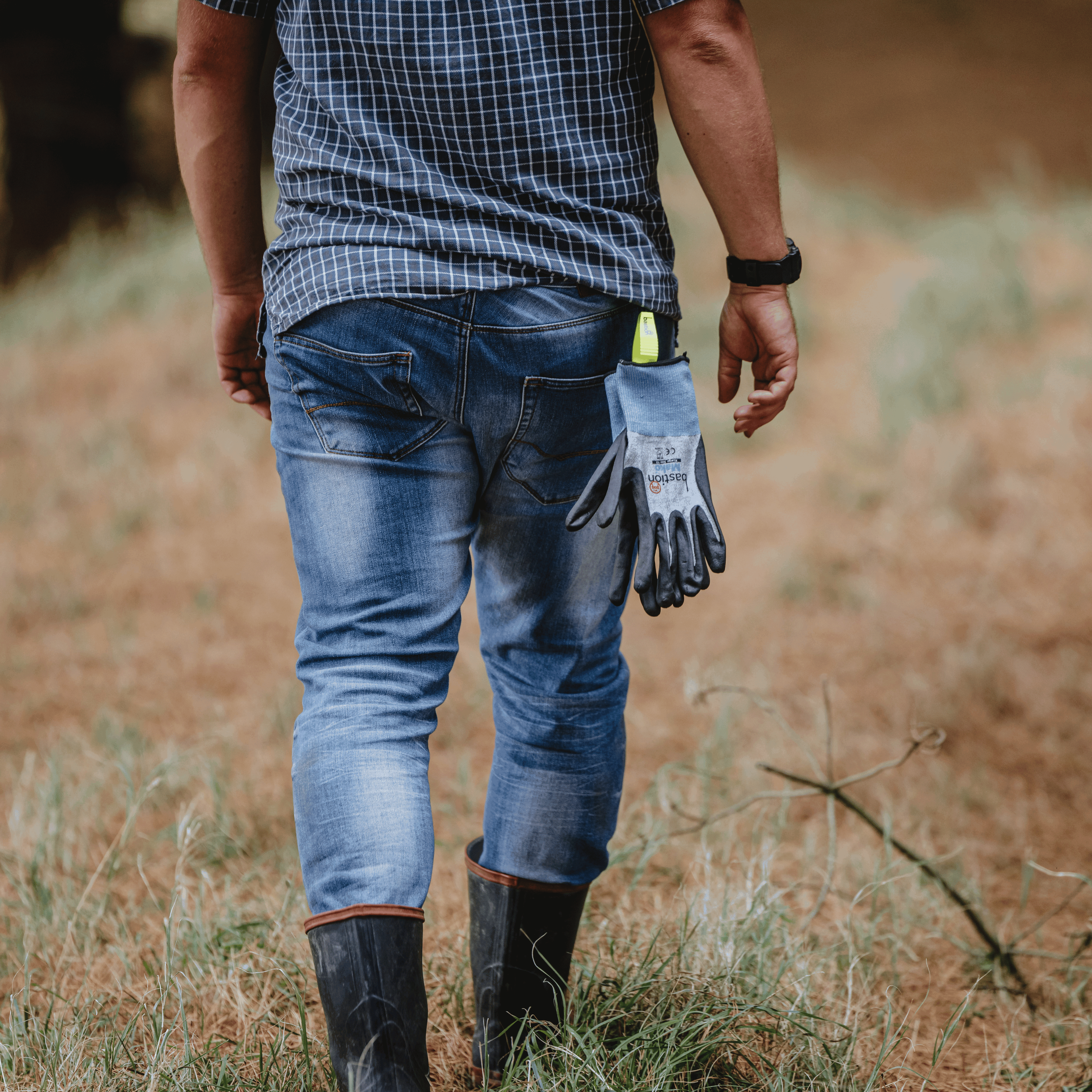 Farmer walking away wearing a Bastion Glove Clip, which is holding Bastion Mako Gloves