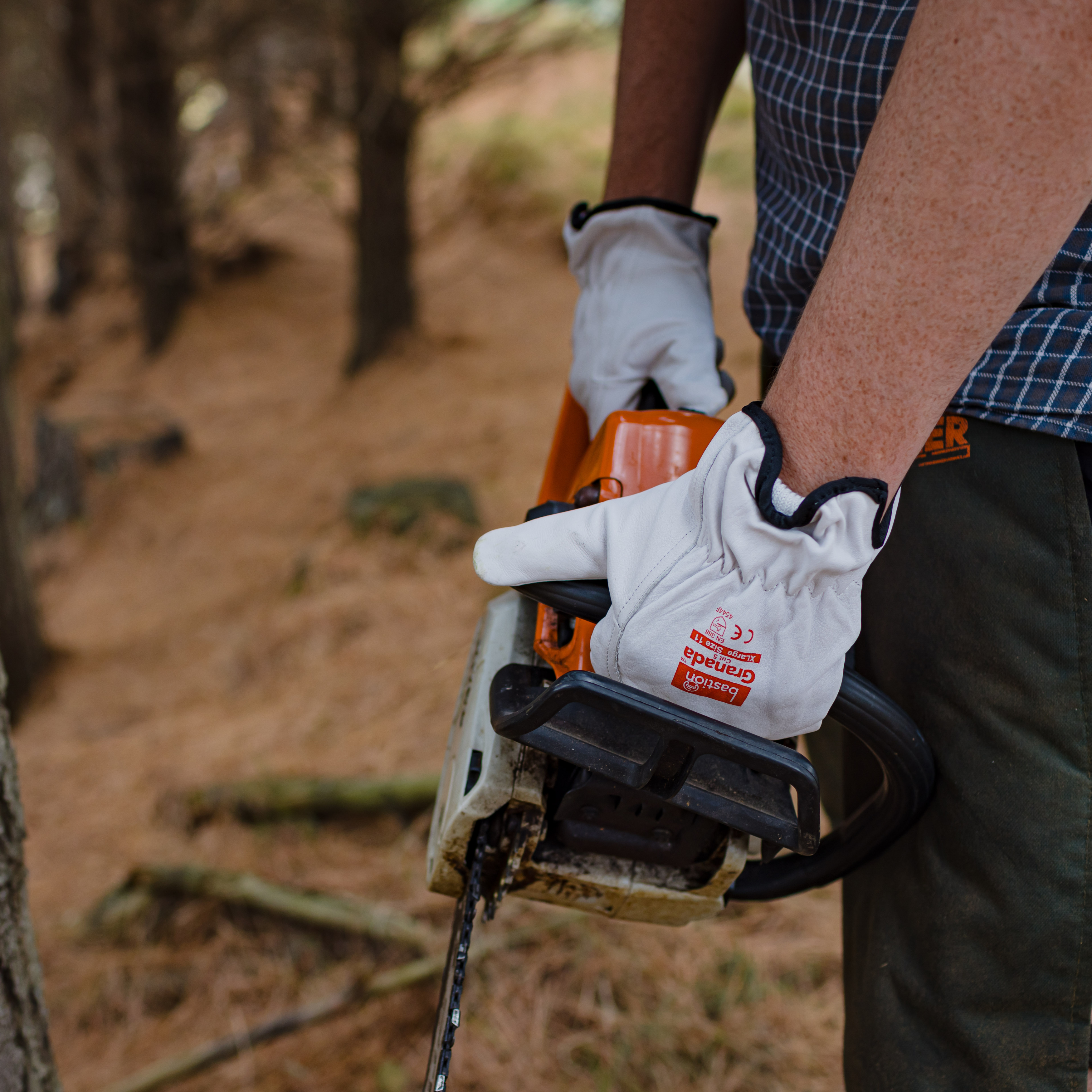 An arborist wearing Bastion Granada Gloves holding a chainsaw