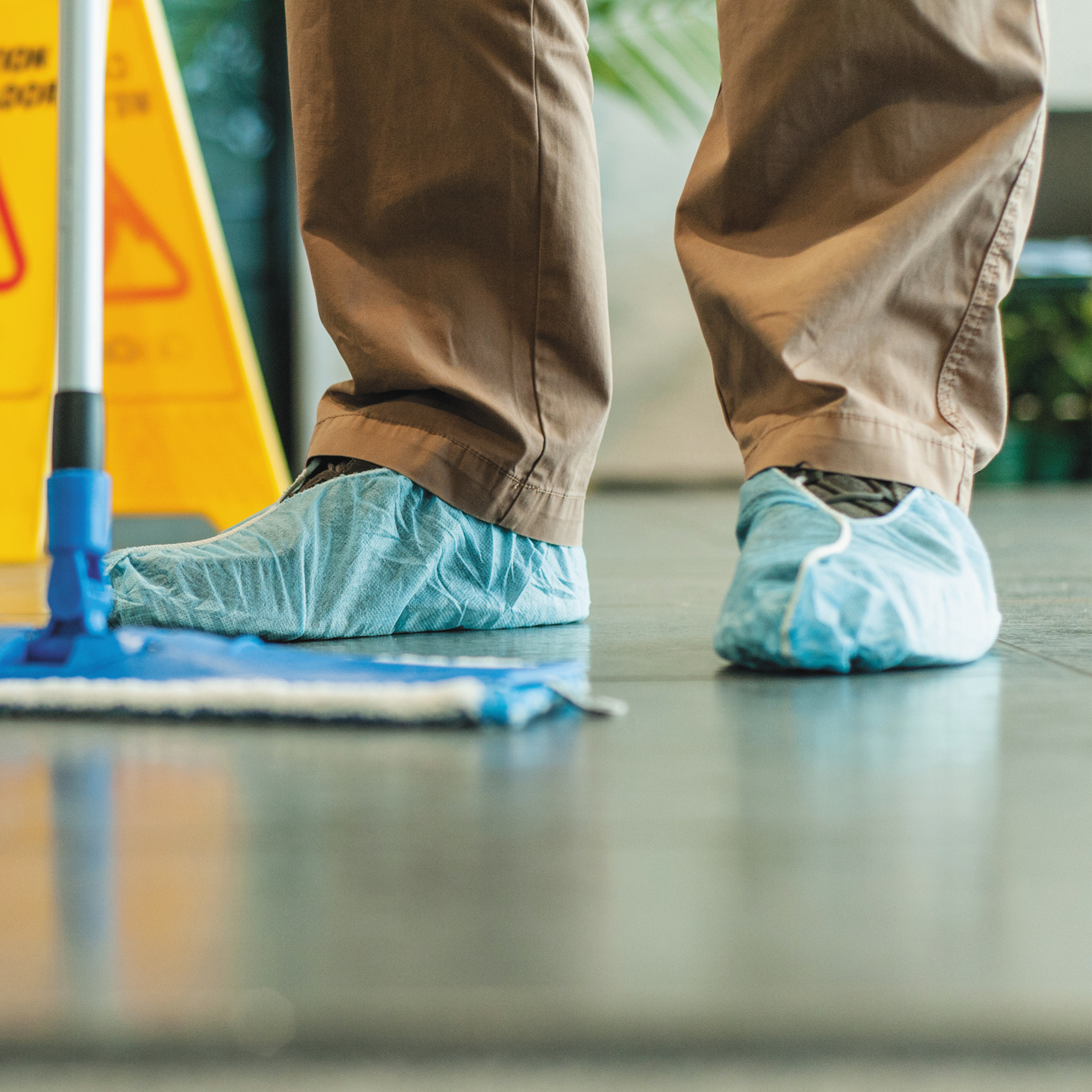 Man mopping the floor, close up of his feet wearing overshoes