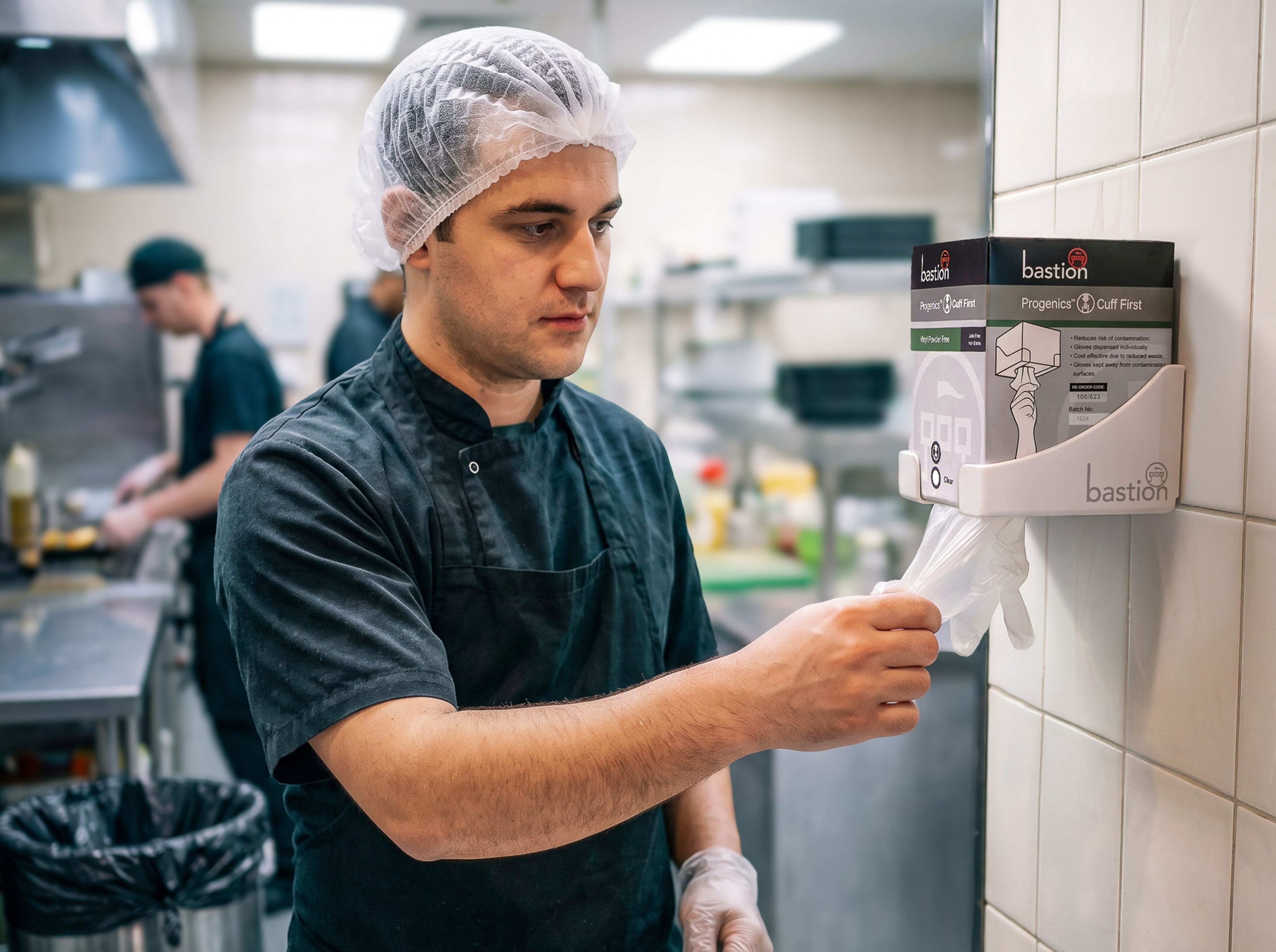 Kitchen hand reaching for progenics vinyl gloves.