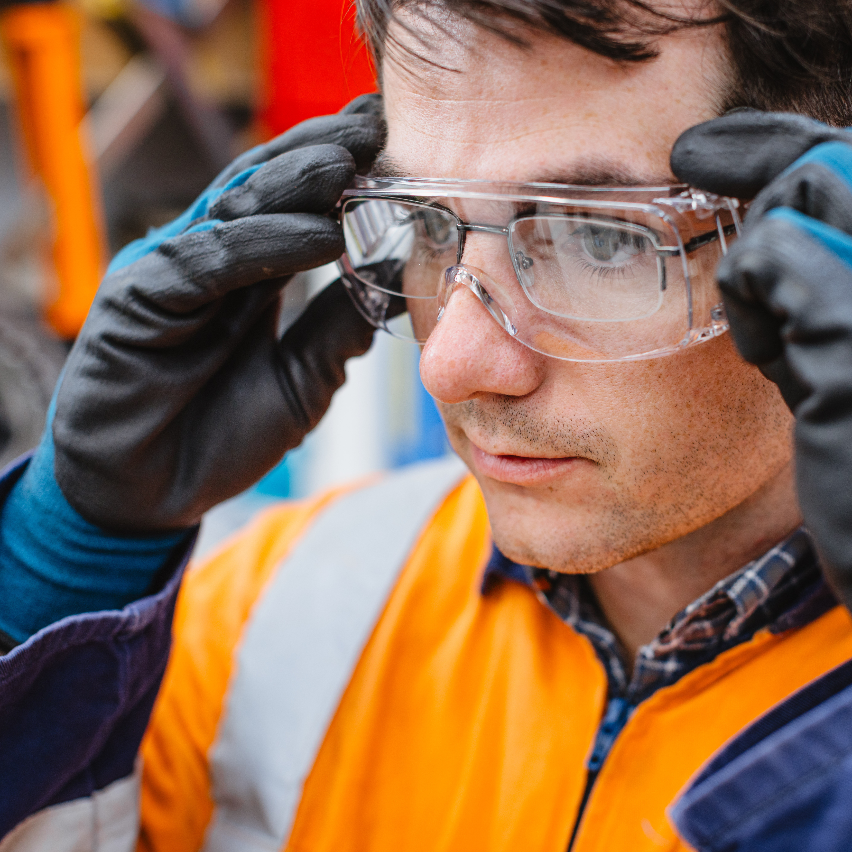 A man putting on safety glasses over his prescription glasses