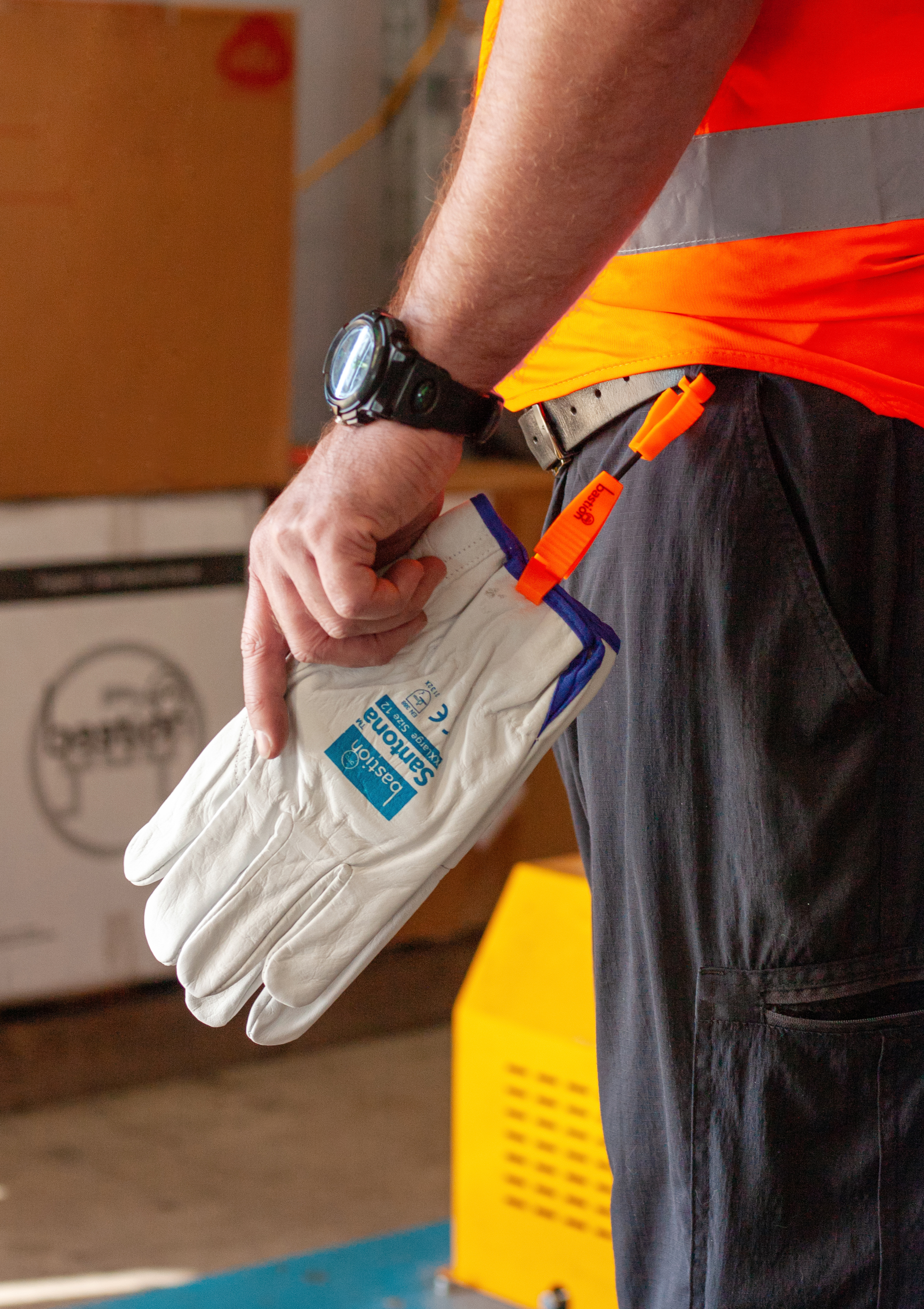 leather industrial gloves hanging from worker in high vis shirts belt using a Bastion glove clip.