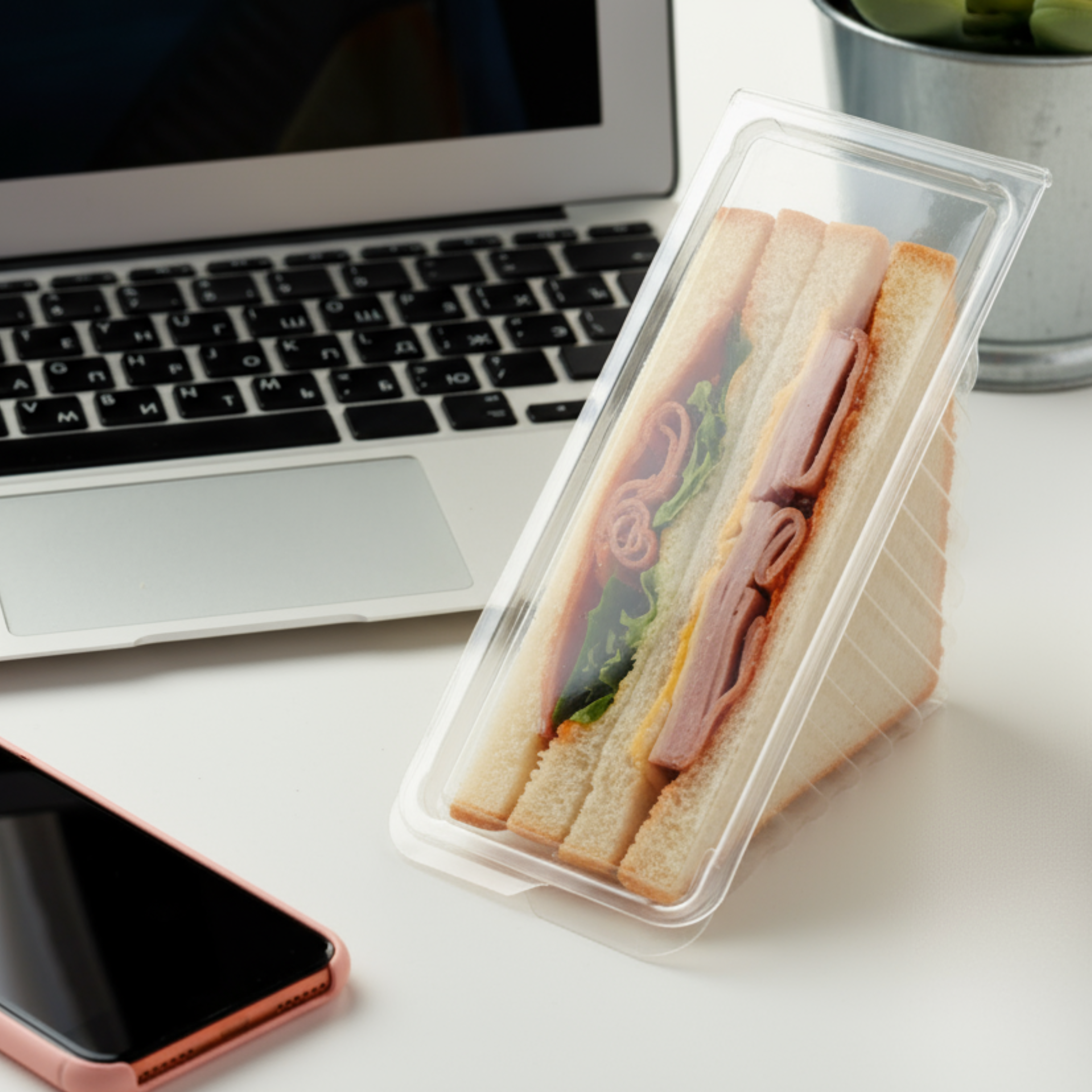 A sandwich sitting on a computer desk, ready for lunch