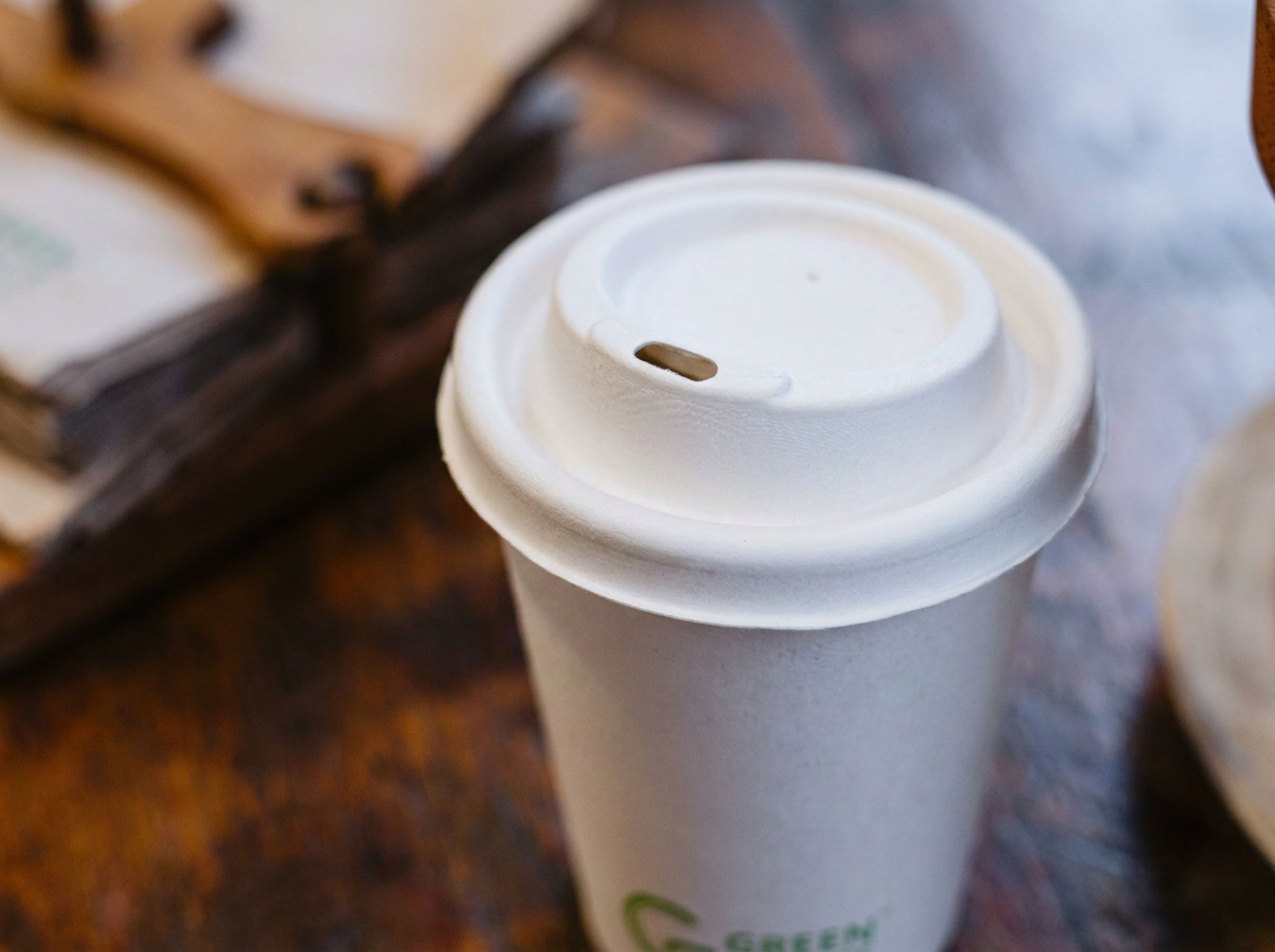 Green Choice Sugarcane hot cup lid on a Green Choice single-wall hot cup sitting on a table