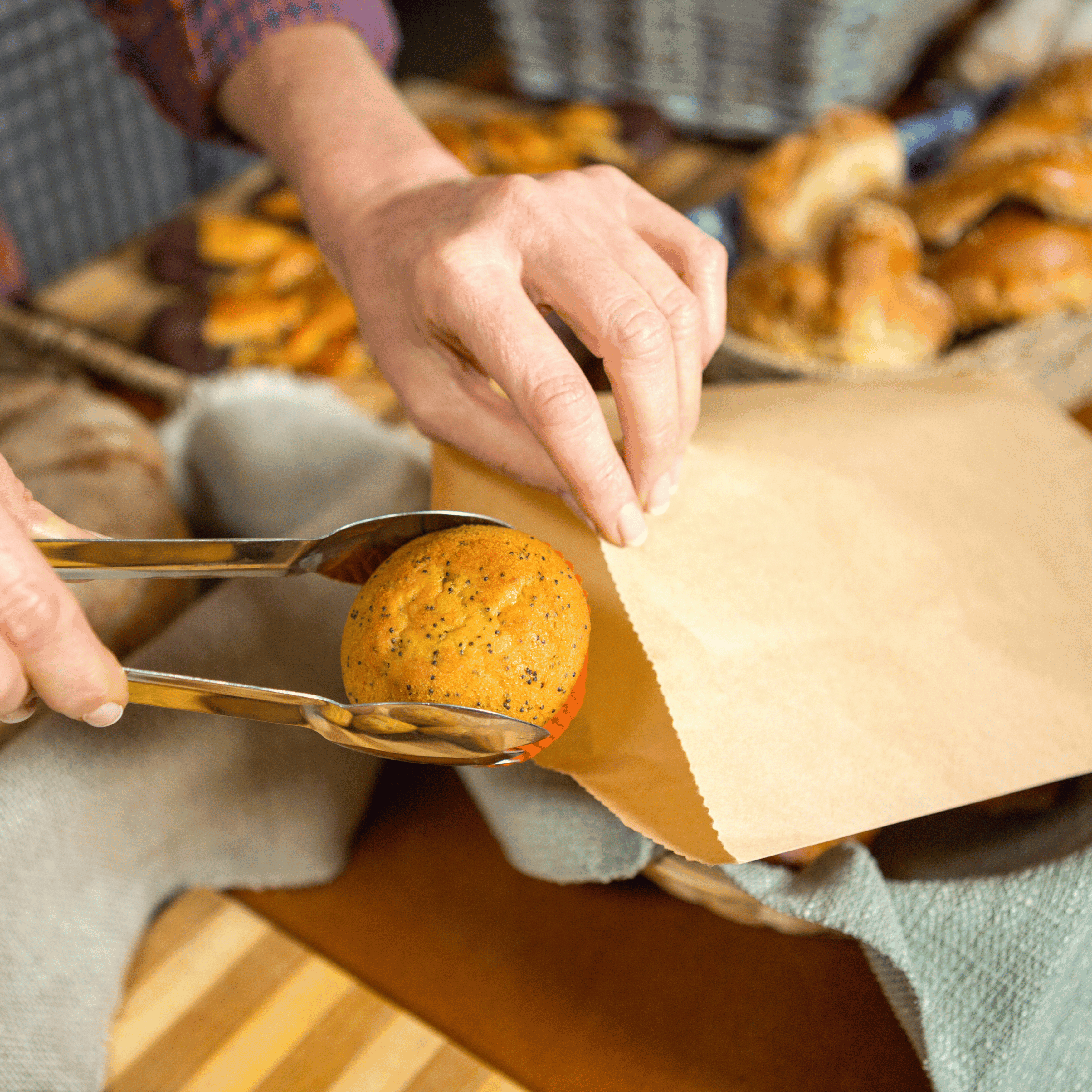 Someone is putting a muffin into a Green Choice brown paper bag