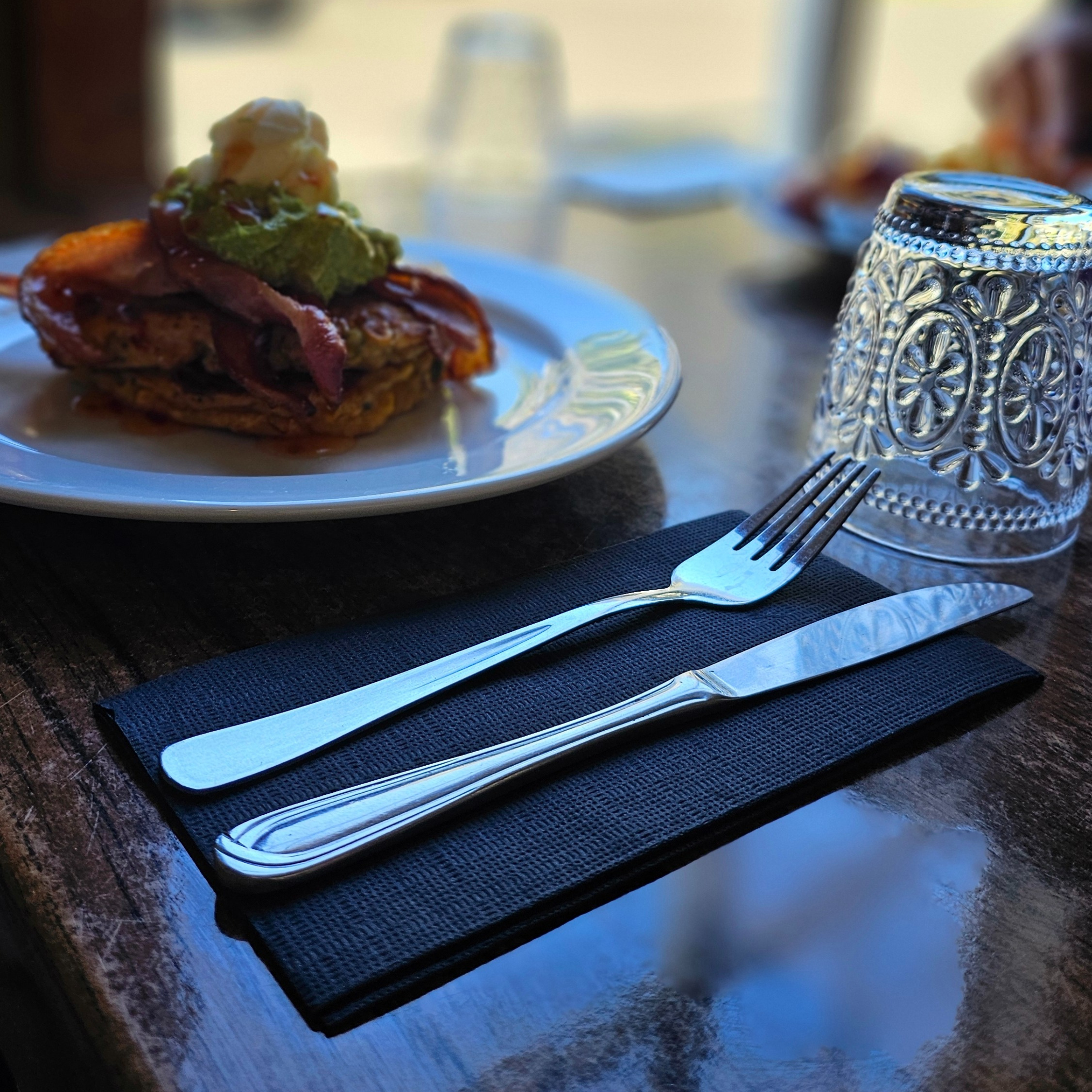 Knife and fork sitting on a Green Choice Quilted Black napkin next to a meal ready to eat.