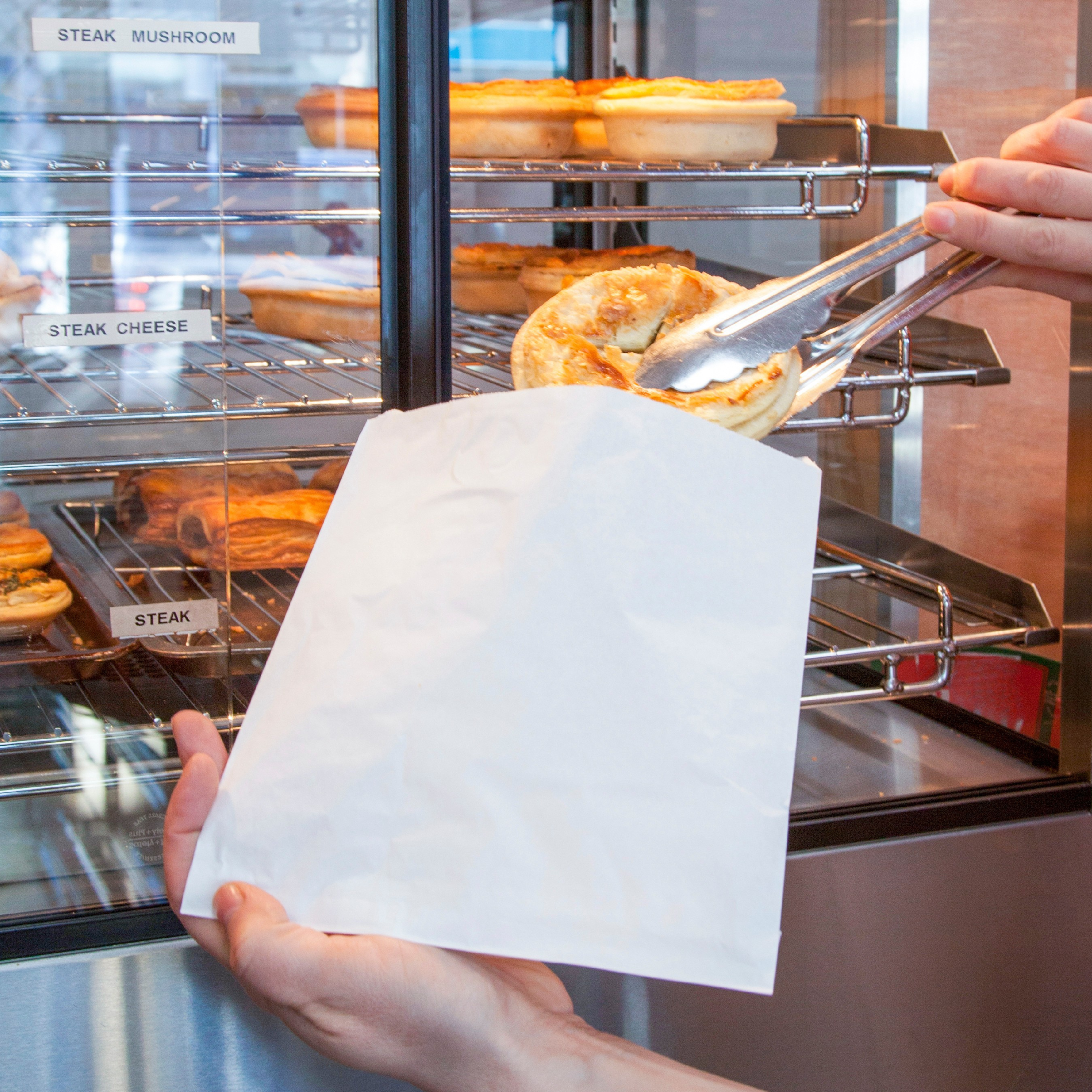Someone is putting a pie into a Green Choice Greaseproof paper bag
