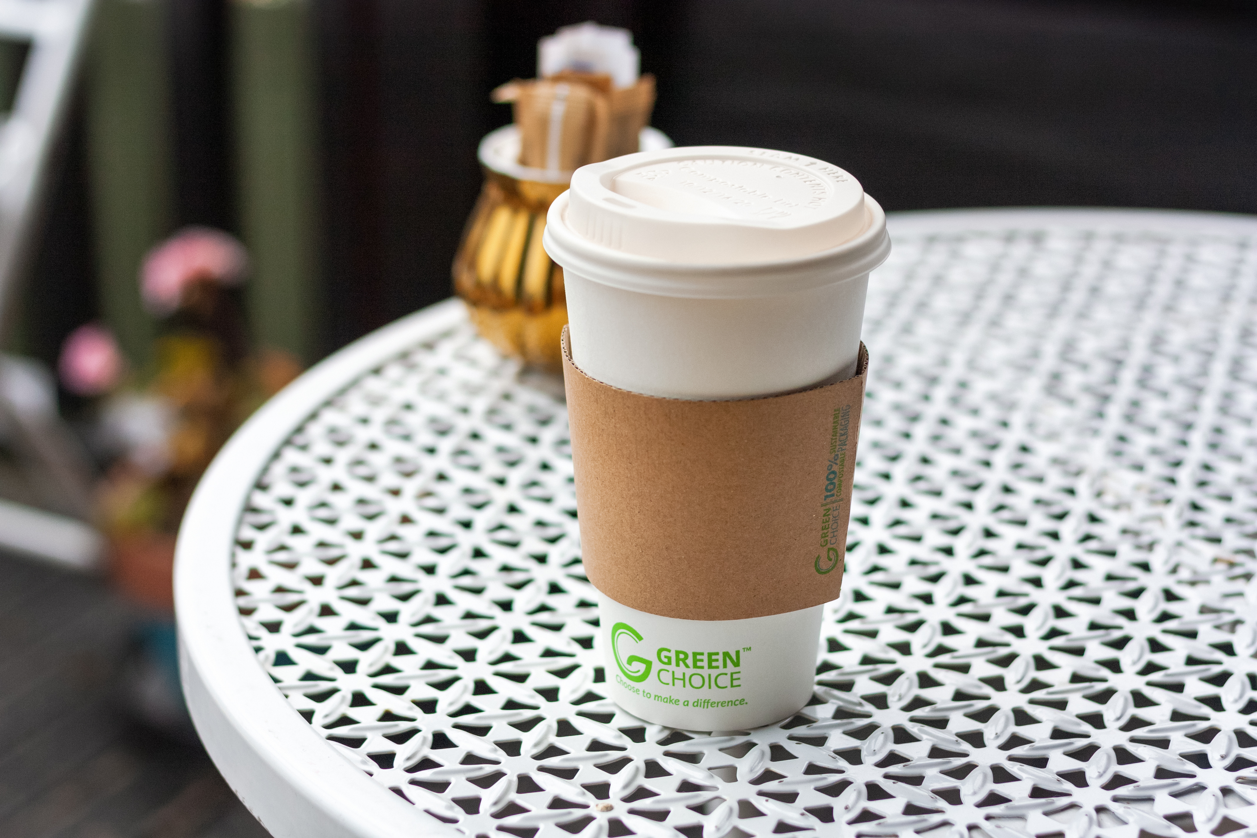 A White Green Choice cup sitting on a white cafe table