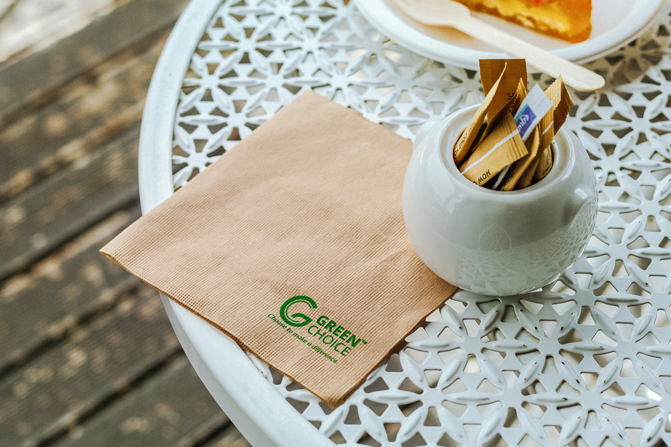 A close-up of a Green Choice kraft napkin sitting on a white cafe table
