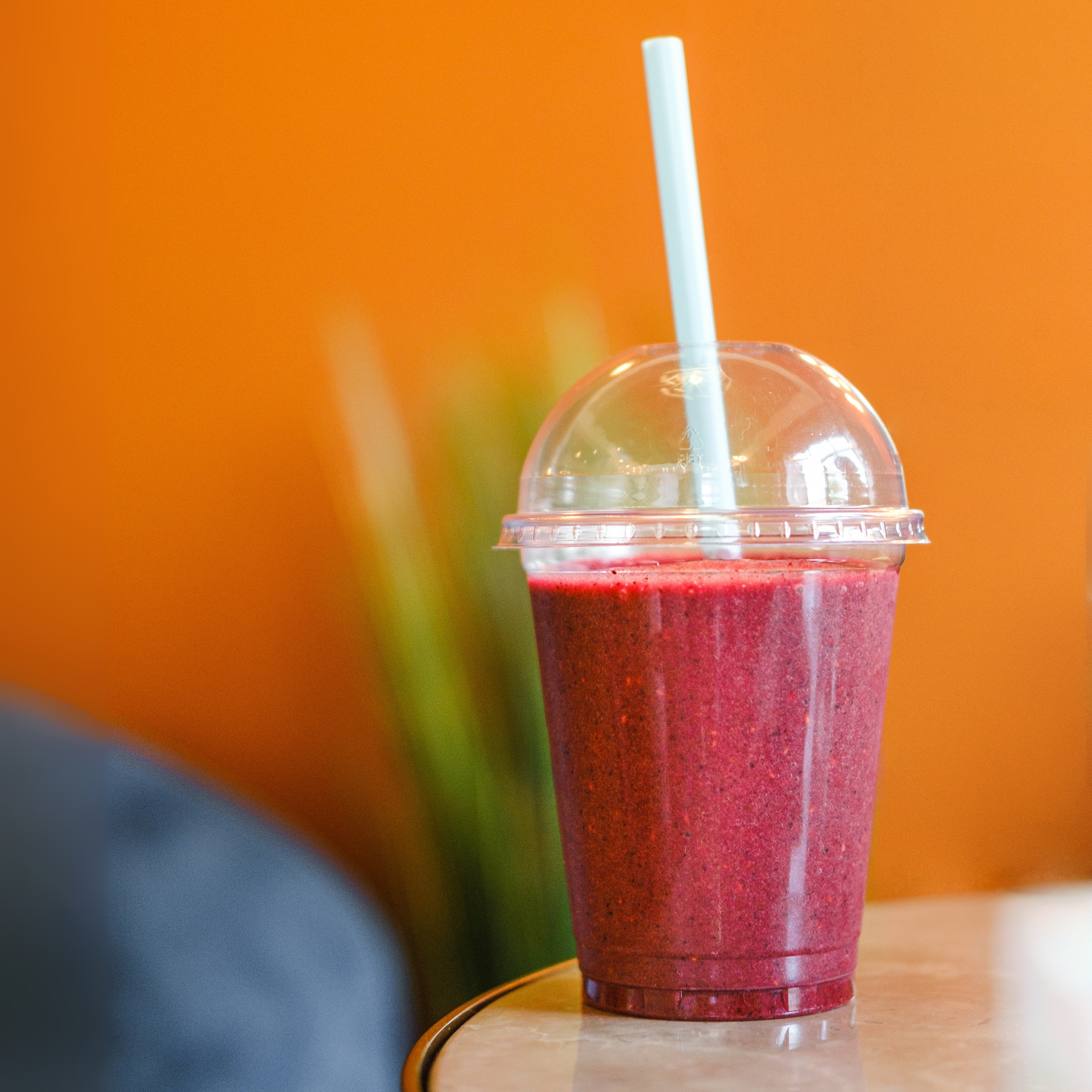 Smoothie is a takeaway cup sitting on a table at a cafe