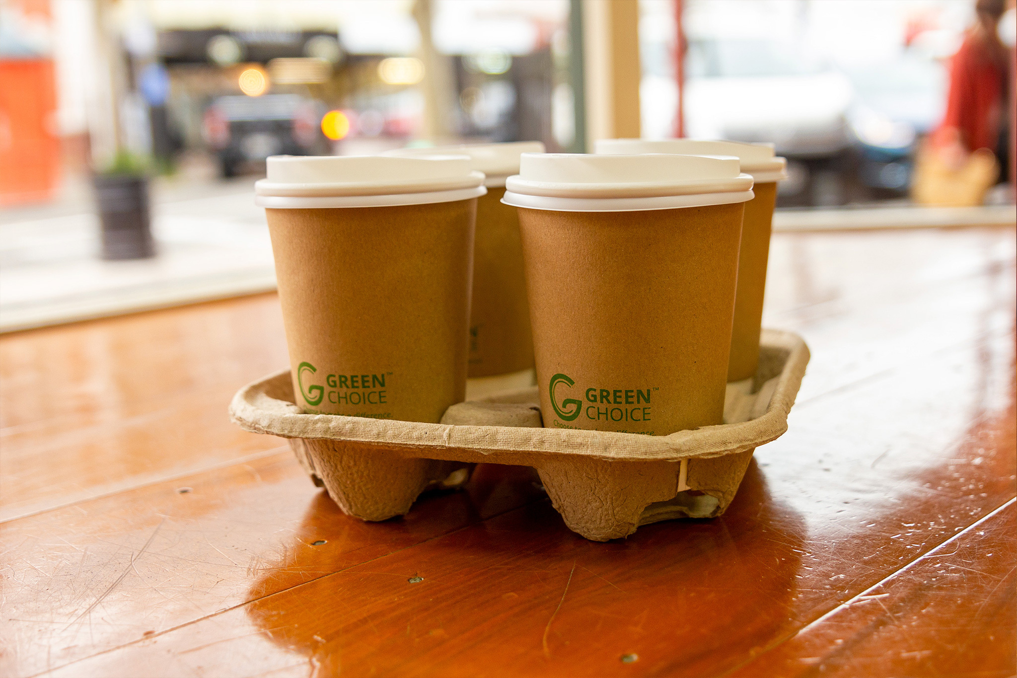 Green Choice pulp 4 cup holder holding 4 Green Choice double wall hot cups with lids sitting on a table