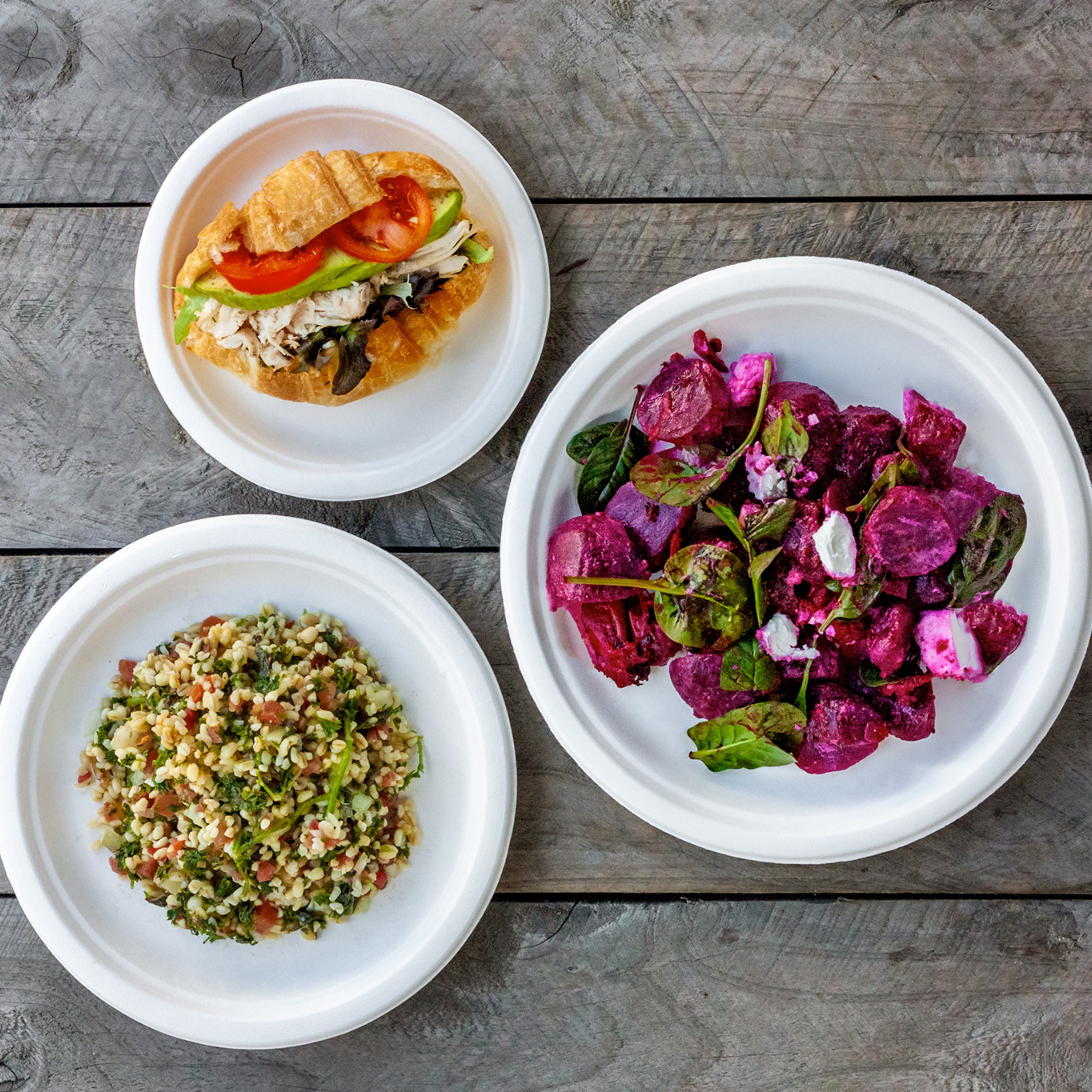 a bird's eye view of 3 Green Choice Sugar cane plates filled with salads
