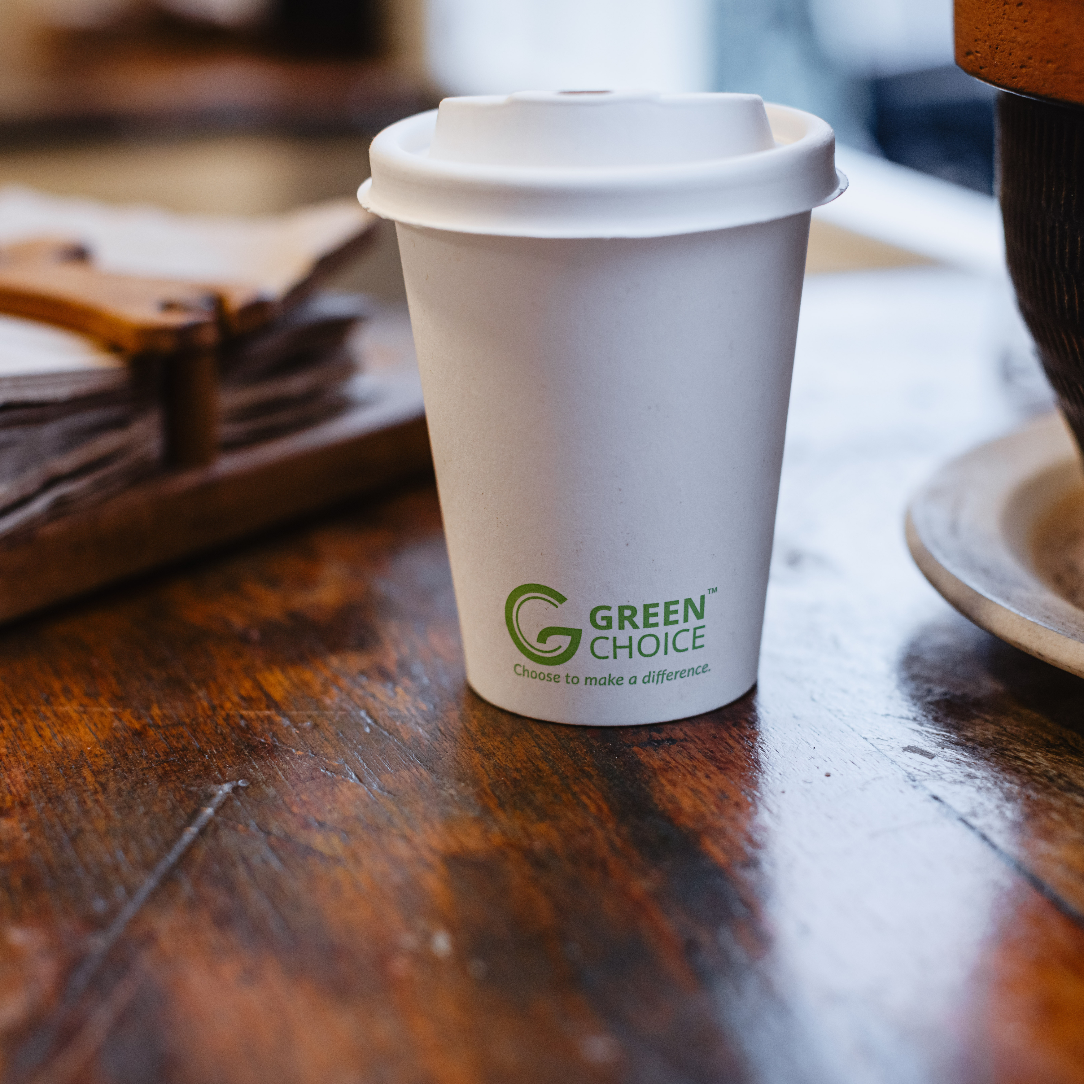 Green Choice Sugarcane hot cup lid on a Green Choice single-wall hot cup sitting on a table