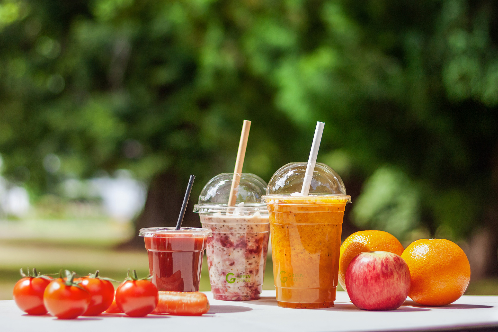 Group of Clear PLA Green Choice with dome and flat lids. surrounded by fruit and veg. bright light. outdoor setting